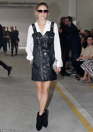 Olivia Palermo wearing Grey Snake Leather Clutch, Black Suede Ankle Boots, White Silk Button Down Blouse, Black Leather Overall Dress