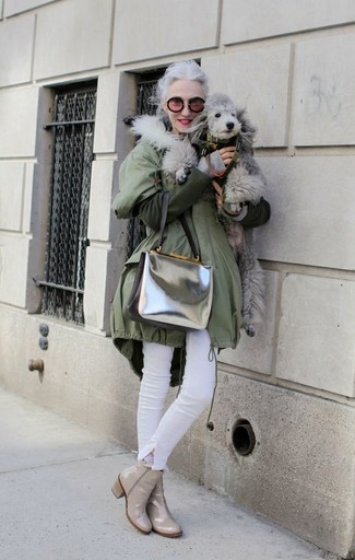 Linda Rodin wearing Silver Leather Crossbody Bag, Beige Leather Ankle Boots, White Skinny Jeans, Olive Parka