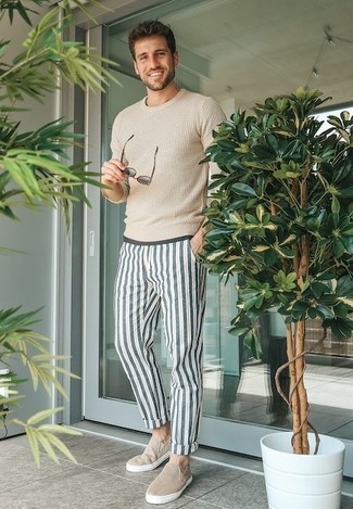 White and Navy Vertical Striped Chinos Outfits: If it's ease and practicality that you love in menswear, reach for a beige crew-neck sweater and white and navy vertical striped chinos. A pair of beige canvas slip-on sneakers is a wonderful option to finish off your ensemble.