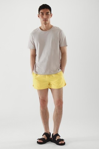 Mustard Sports Shorts Outfits For Men: Pair a beige crew-neck t-shirt with mustard sports shorts to create a city casual and absolutely dapper ensemble. A pair of black canvas sandals will instantly play down a smart outfit.