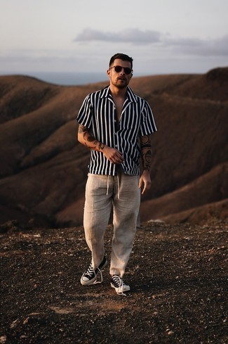 Men's Black and White Vertical Striped Short Sleeve Shirt, Khaki Linen Chinos, Black and White Canvas Low Top Sneakers, Black Sunglasses
