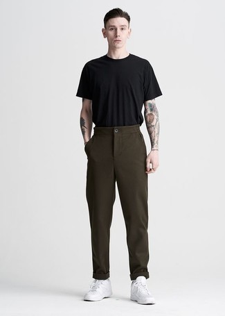 Dark Brown Chinos Outfits: Fashionable and comfortable, this casual pairing of a black crew-neck t-shirt and dark brown chinos provides wonderful styling possibilities. Rock a pair of white leather low top sneakers and you're all set looking killer.