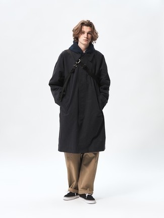Men's Outfits 2022: Consider teaming a black raincoat with khaki chinos if you wish to look casual and cool without making too much effort. The whole ensemble comes together when you complement this look with black and white canvas low top sneakers.