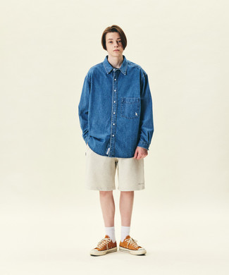 Blue Denim Shirt Outfits For Men: Flaunt your prowess in men's fashion in this street style combination of a blue denim shirt and beige sports shorts. Play up the dressiness of your ensemble a bit by rounding off with orange canvas low top sneakers.