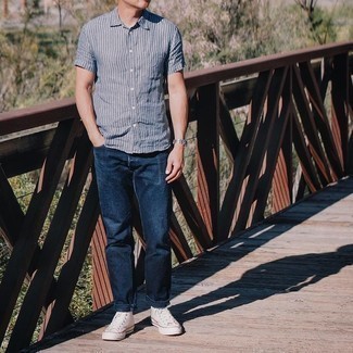 Blue Vertical Striped Short Sleeve Shirt Outfits For Men: Flaunt your skills in men's fashion by teaming a blue vertical striped short sleeve shirt and navy jeans for a casual outfit. A pair of white canvas high top sneakers brings just the right amount of stylish nonchalance to this look.