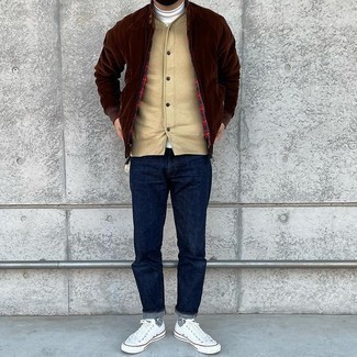White and Navy Canvas Low Top Sneakers Outfits For Men: Swing into something practical yet modern in a dark brown bomber jacket and navy jeans. Let your sartorial expertise really shine by rounding off your look with white and navy canvas low top sneakers.