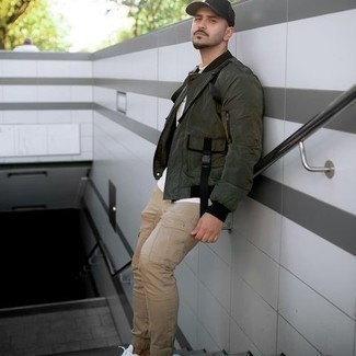 Dark Green Bomber Jacket Outfits For Men: This off-duty combo of a dark green bomber jacket and khaki cargo pants couldn't possibly come across other than seriously dapper. Add white canvas low top sneakers to the mix et voila, this outfit is complete.