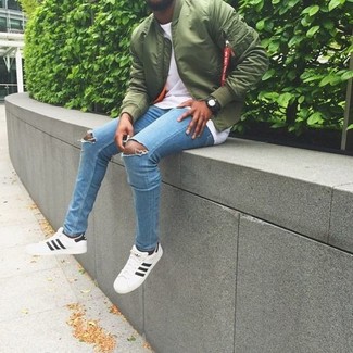 Dark Green Bomber Jacket Outfits For Men: One of the coolest ways for a man to style a dark green bomber jacket is to combine it with light blue ripped skinny jeans for a casual combo. White low top sneakers are an easy way to breathe an extra touch of sophistication into this look.