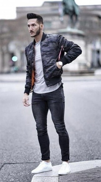 Navy Camouflage Bomber Jacket Outfits For Men: The styling capabilities of a navy camouflage bomber jacket and charcoal skinny jeans ensure they'll be on regular rotation. On the fence about how to complement this ensemble? Wear white canvas low top sneakers to dial it up a notch.