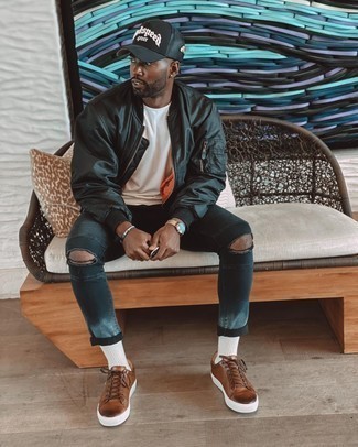 Brown Leather Low Top Sneakers Outfits For Men: This combo of a black bomber jacket and black ripped skinny jeans is undeniable proof that a safe casual outfit doesn't have to be boring. A pair of brown leather low top sneakers immediately revs up the style factor of this ensemble.