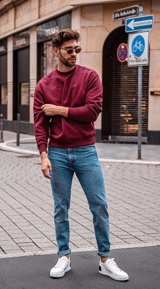 Red Sweatshirt Outfits For Men: Reach for a red sweatshirt and blue jeans for an on-trend, laid-back look. Let your sartorial skills really shine by finishing off this look with white and black canvas low top sneakers.