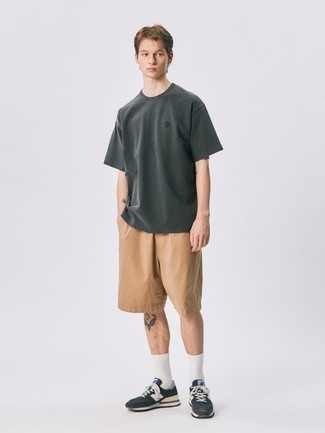 66 Relaxed Summer Outfits For Men: A charcoal crew-neck t-shirt and tan shorts are the kind of a never-failing off-duty getup that you need when you have zero time to spare. Dark brown athletic shoes will give a more laid-back aesthetic to an otherwise standard look. Come warm sunny days you're looking for an ensemble to keep you fresh and dapper –– this look is just the right one.