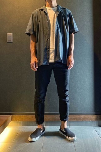 Black Canvas Slip-on Sneakers Outfits For Men: Pair a charcoal short sleeve shirt with black jeans for a casual outfit with a modern spin. We love how a pair of black canvas slip-on sneakers makes this outfit whole.
