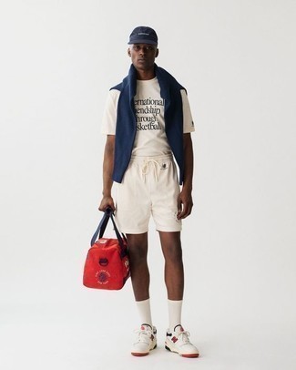 Sports Shorts Outfits For Men: A navy crew-neck sweater and sports shorts are awesome menswear must-haves to add to your current off-duty fashion mix. White and red leather low top sneakers will bring a dose of class to an otherwise mostly dressed-down ensemble.