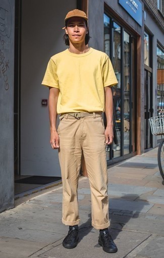 Beige Chinos Hot Weather Outfits: Go for a pared down but casual and cool choice by putting together a yellow crew-neck t-shirt and beige chinos. Complete this ensemble with a pair of black leather low top sneakers for extra style points.