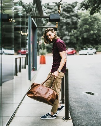 Brown Duffle Bag Outfits For Men: Such essentials as a burgundy crew-neck t-shirt and a brown duffle bag are the ideal way to introduce toned down dapperness into your casual styling lineup. Inject an extra dose of polish into your outfit by slipping into navy and white suede low top sneakers.