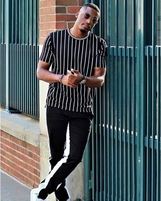 Black Vertical Striped Crew-neck T-shirt Outfits For Men: Pair a black vertical striped crew-neck t-shirt with black and white chinos to achieve a casual and cool ensemble. A pair of white canvas low top sneakers looks right at home with this ensemble.