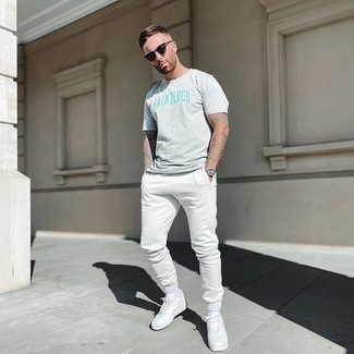 White Sweatpants Outfits For Men: A grey print crew-neck t-shirt and white sweatpants paired together are a match made in heaven. White leather low top sneakers are an effective way to infuse a dose of polish into this outfit.