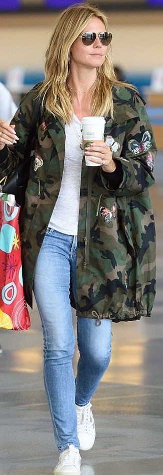 Pair a dark green camouflage parka with light blue skinny jeans for an easy-to-style outfit. White leather low top sneakers pull the look together.
