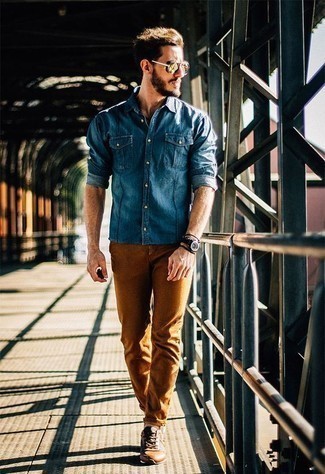 Navy Denim Shirt Outfits For Men: Why not marry a navy denim shirt with tobacco chinos? As well as super practical, these two pieces look amazing when worn together. A cool pair of tobacco leather low top sneakers pulls this ensemble together.