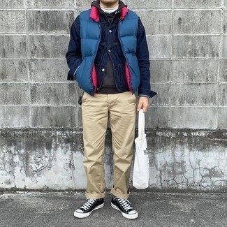 Men's Outfits 2021: This combo of a blue quilted gilet and khaki chinos is uber stylish and provides a casually stylish look. When it comes to footwear, this look pairs well with black and white canvas low top sneakers.
