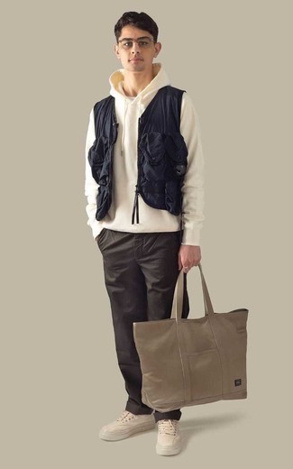 Tan Canvas Tote Bag Outfits For Men: A navy gilet and a tan canvas tote bag are bona fide must-haves if you're crafting a casual wardrobe that holds to the highest sartorial standards. A pair of beige canvas low top sneakers effortlessly dials up the classy factor of your outfit.