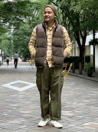 Brown Quilted Gilet Outfits For Men: Go for a brown quilted gilet and olive cargo pants to assemble an incredibly stylish and current off-duty outfit. A pair of white canvas low top sneakers is a good pick to complete your outfit.