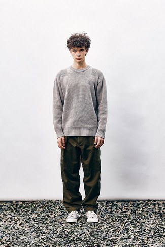 Men's Outfits 2022: A grey crew-neck sweater looks so laid-back and cool when combined with dark brown chinos. Why not complement your look with beige canvas low top sneakers for a more laid-back finish?