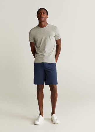 White Leather Low Top Sneakers Hot Weather Outfits For Men: For a laid-back getup, consider wearing a grey crew-neck t-shirt and navy shorts — these items fit perfectly well together. A pair of white leather low top sneakers looks awesome finishing off your look.