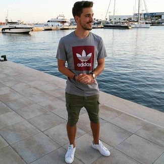 White Leather Low Top Sneakers Hot Weather Outfits For Men: A grey print crew-neck t-shirt and olive shorts are the kind of a fail-safe casual look that you so desperately need when you have zero time. White leather low top sneakers pull the outfit together.