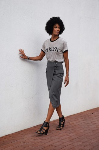 Charcoal Print Crew-neck T-shirt Outfits For Women: For a look that's pared-down but can be flaunted in a variety of different ways, pair a charcoal print crew-neck t-shirt with a grey midi skirt. Finish this look with a pair of black leather heeled sandals to spice things up.