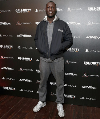 Stormzy wearing White Athletic Shoes, Grey Sweatpants, Grey Hoodie, Black Bomber Jacket