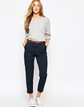 Black Chinos Outfits For Women: Rushed mornings call for a straightforward yet stylish outfit, such as a grey sweatshirt and black chinos. Introduce a pair of white canvas low top sneakers to the mix and the whole outfit will come together.