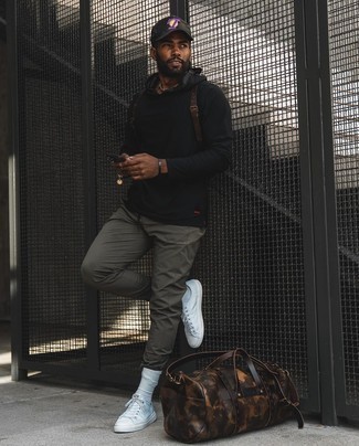 Dark Brown Leather Duffle Bag Outfits For Men: Look stunning without exerting much effort by opting for a black hoodie and a dark brown leather duffle bag. Rev up your whole getup by finishing with a pair of white canvas low top sneakers.