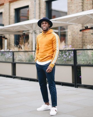 Orange Hoodie Outfits For Men: This combo of an orange hoodie and navy chinos is solid proof that a safe casual look can still look razor-sharp. If you don't know how to round off, introduce a pair of white print canvas low top sneakers to the mix.