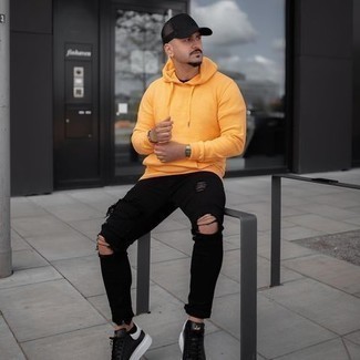 Orange Hoodie Outfits For Men: If you gravitate towards comfort dressing, why not opt for an orange hoodie and black ripped jeans? Complement this look with a pair of black and white leather low top sneakers to effortlessly amp up the wow factor of your look.