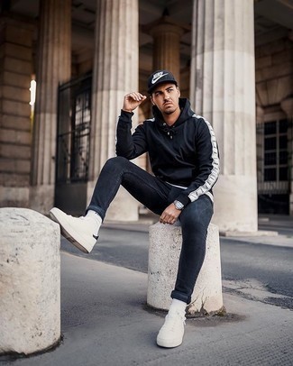 Navy Print Baseball Cap Outfits For Men: Display your credentials in men's fashion by opting for this contemporary combination of a black hoodie and a navy print baseball cap. Complement this getup with a pair of white and black canvas low top sneakers to take things up a notch.