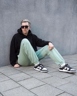 Black Hoodie Outfits For Men: If you enjoy a more casual approach to dressing up, why not wear a black hoodie and mint sweatpants? Don't know how to complement this outfit? Round off with a pair of white and black leather low top sneakers to kick it up a notch.