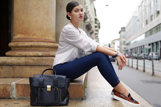 Black Slip-on Sneakers Outfits For Women: This pairing of a white polka dot long sleeve blouse and navy skinny jeans is on the off-duty side but guarantees that you look absolutely stylish and elegant. A pair of black slip-on sneakers easily steps up the street cred of this look.