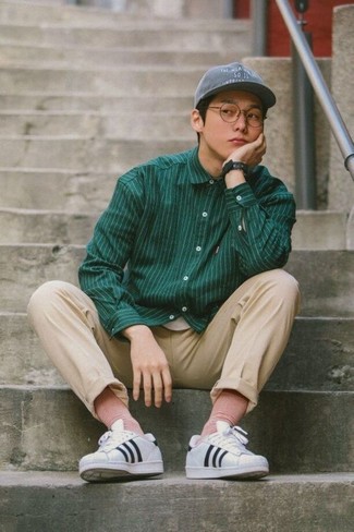 Charcoal Baseball Cap Outfits For Men: This combination of a dark green vertical striped long sleeve shirt and a charcoal baseball cap speaks comfort and off-duty cool. To add more class to your outfit, finish with white and black horizontal striped leather low top sneakers.