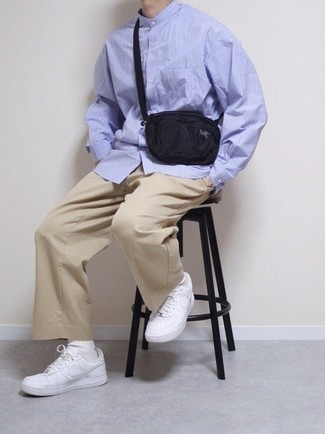 Black Canvas Fanny Pack Outfits For Men: If the situation permits a casual getup, you can easily dress in a light blue vertical striped long sleeve shirt and a black canvas fanny pack. A pair of white leather low top sneakers adds an elegant aesthetic to the ensemble.