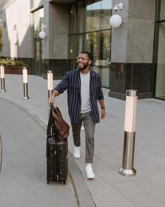 Black Suitcase Outfits For Men: For a laid-back and cool look, reach for a navy and white vertical striped long sleeve shirt and a black suitcase — these items fit really well together. You could follow a more elegant route when it comes to shoes by slipping into white canvas low top sneakers.