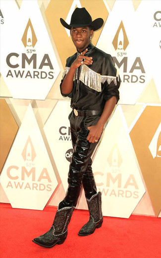 Lil Nas X wearing Black Leather Long Sleeve Shirt, Black Leather Jeans, Black Embroidered Leather Cowboy Boots, Black Wool Hat