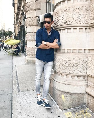 Grey Ripped Jeans Outfits For Men: Want to infuse your closet with some urban menswear style? Try teaming a navy chambray long sleeve shirt with grey ripped jeans. In the footwear department, go for something on the more elegant end of the spectrum by slipping into navy and white suede low top sneakers.