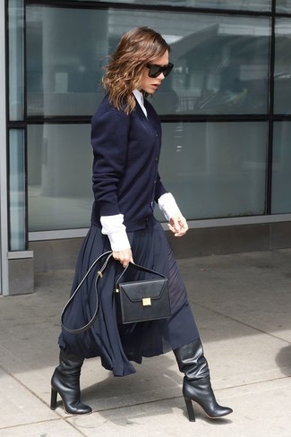Victoria Beckham wearing Black Leather Knee High Boots, Navy Pleated Midi Skirt, White Dress Shirt, Navy Cardigan