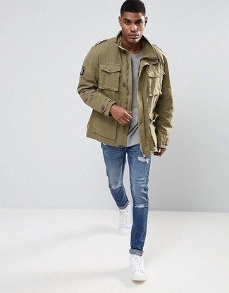 Khaki Military Jacket Outfits For Men: Wear a khaki military jacket with blue ripped jeans to feel self-confident and look trendy. Complete your getup with white canvas low top sneakers et voila, this look is complete.