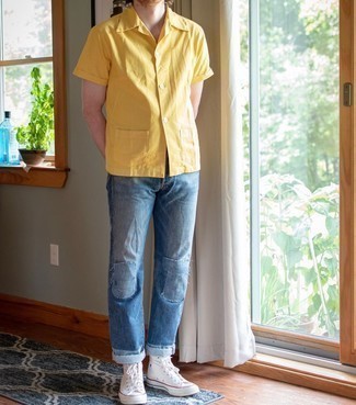 Blue Patchwork Jeans Outfits For Men: Go for a simple but at the same time laid-back and cool outfit pairing a mustard short sleeve shirt and blue patchwork jeans. Ramp up your whole outfit by slipping into white canvas high top sneakers.