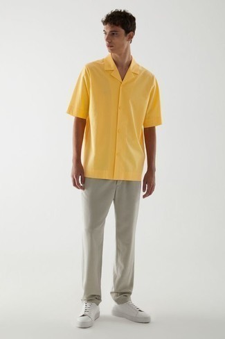 500+ Summer Outfits For Men: Master the cool and casual outfit in a mustard short sleeve shirt and grey chinos. A pair of white leather low top sneakers is a good option to finish this ensemble. As you know, the trick to getting through the hottest time of year is choosing cool combinations like this one.