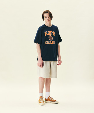121 Relaxed Outfits For Men: If you like relaxed dressing, why not wear this combo of a navy print crew-neck t-shirt and beige sports shorts? To give this ensemble a sleeker feel, complete this getup with orange canvas low top sneakers.