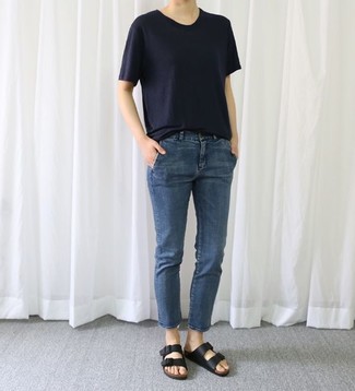 Black Leather Flat Sandals Outfits: This combo of a navy crew-neck t-shirt and navy jeans speaks casual cool and stylish practicality. Add a dose of stylish nonchalance to your getup with black leather flat sandals.
